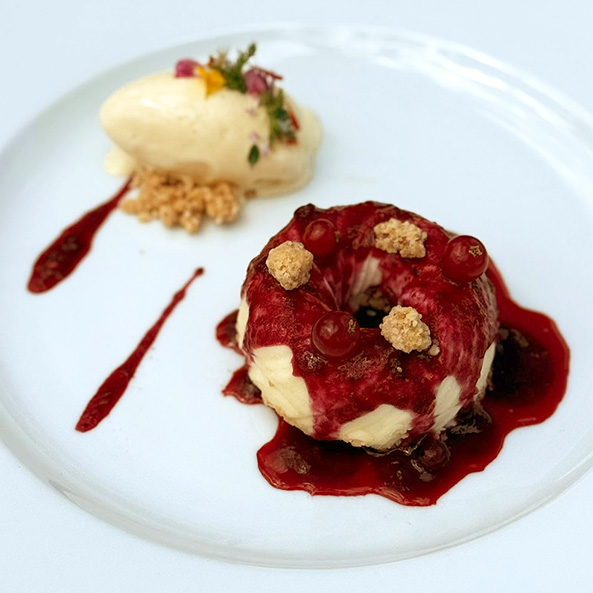 Ein Dessert mit roter Beerensauce auf einem weißen Teller